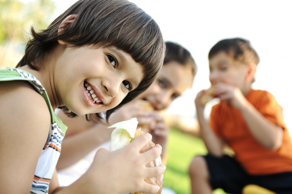small-group-of-children-in-nature-eating-snacks-together-SBI-300912435.jpg