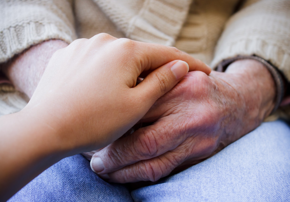 young-caregiver-holding-hands-with-senior-lady-SBI-317477469.jpg